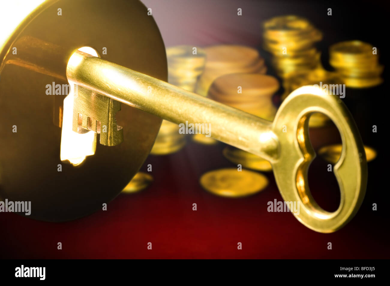 Golden key to the fortune with columns of coins in the background. Stock Photo
