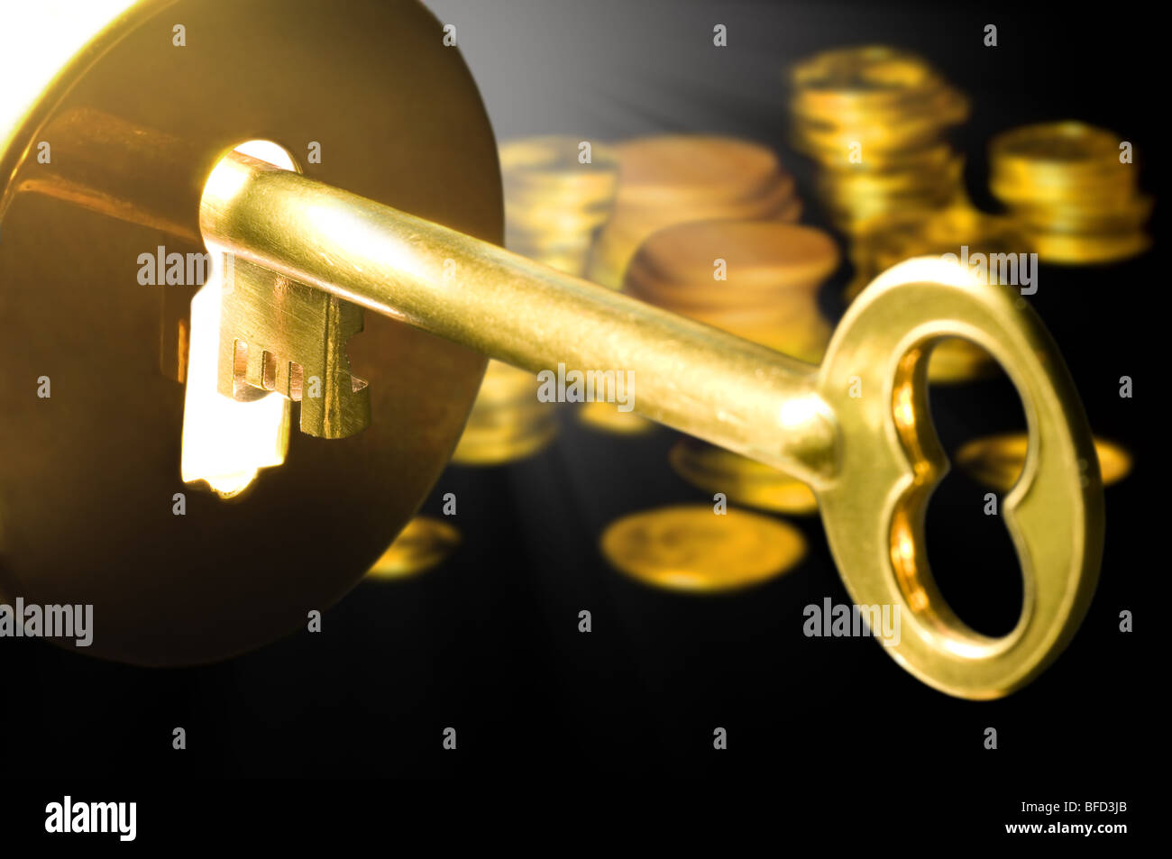 Golden key to the fortune with columns of coins in the background. Stock Photo