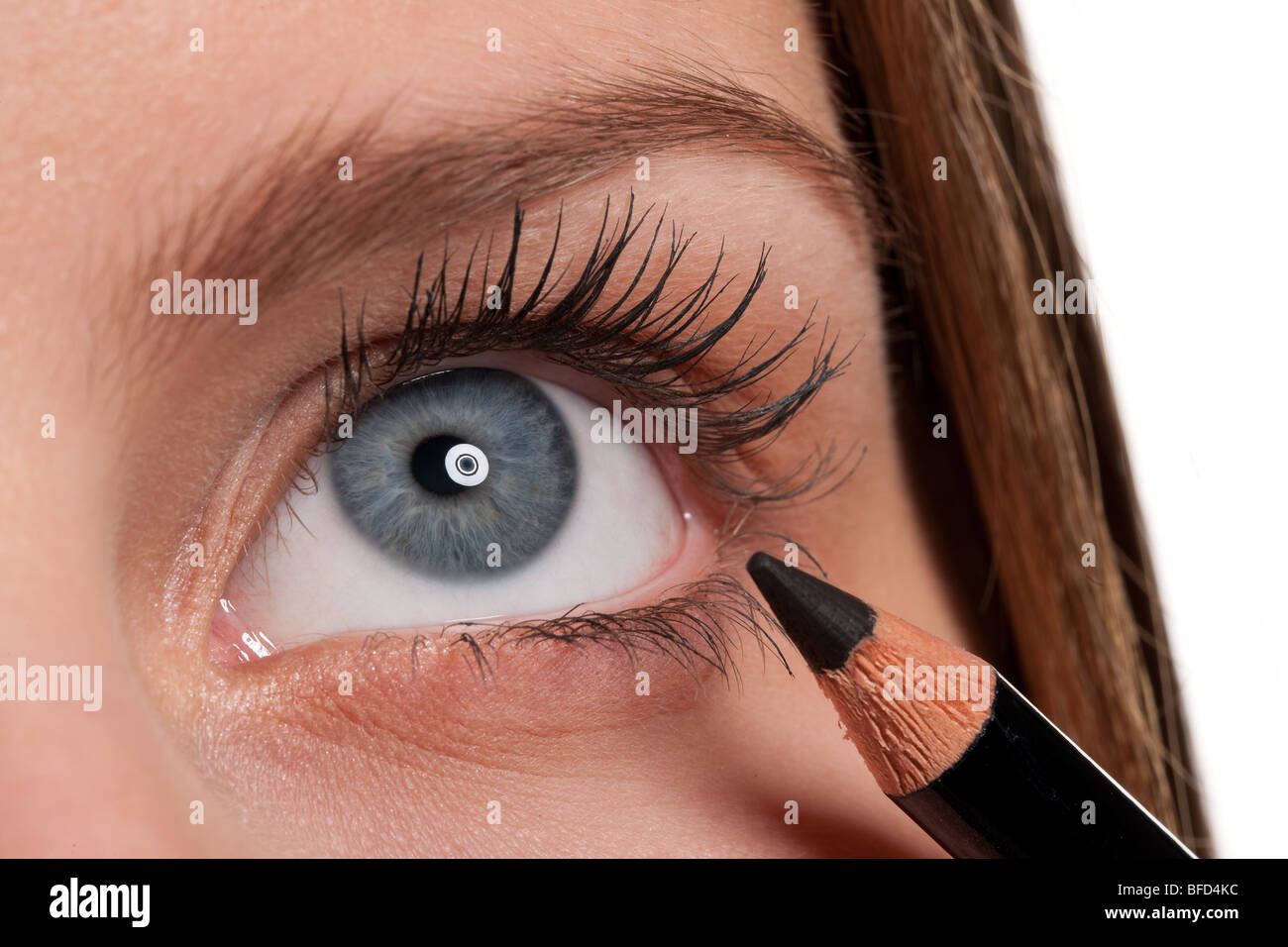 Close-up of blue eye, woman applying black make-up pencil, macro lens Stock Photo