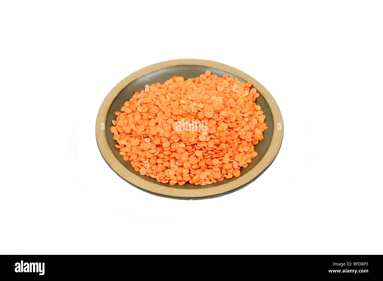 Red Split lentils on a platter against a white background Stock Photo