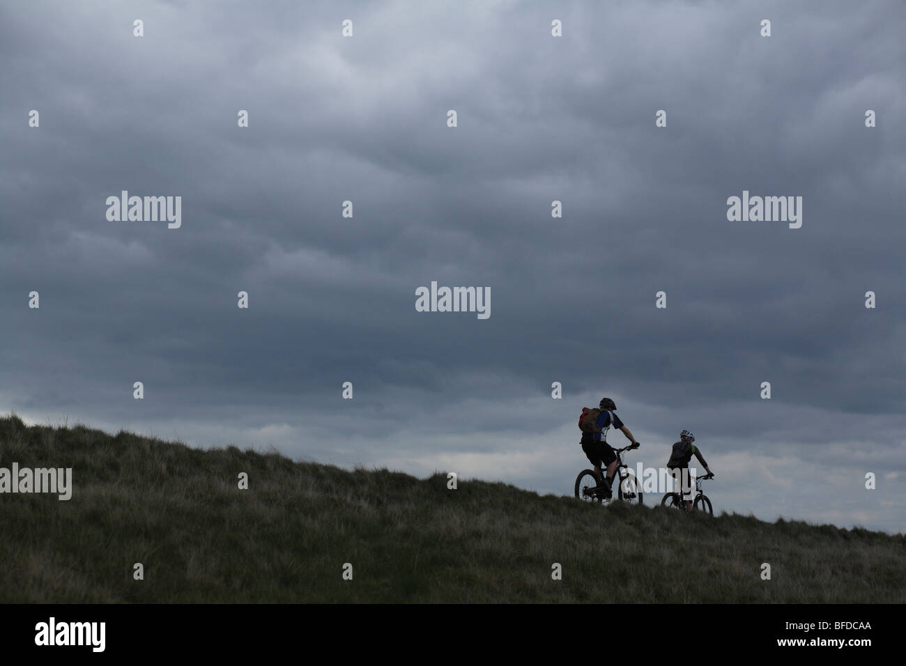 A couple mountain bikes along the crest of a hill under cloudy skies in Yorkshire, England. Stock Photo