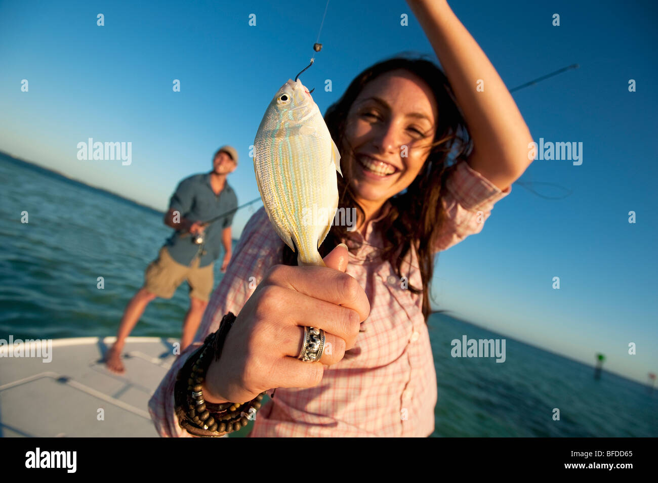 A woman smiles and holds up a small fish in Florida. Stock Photo
