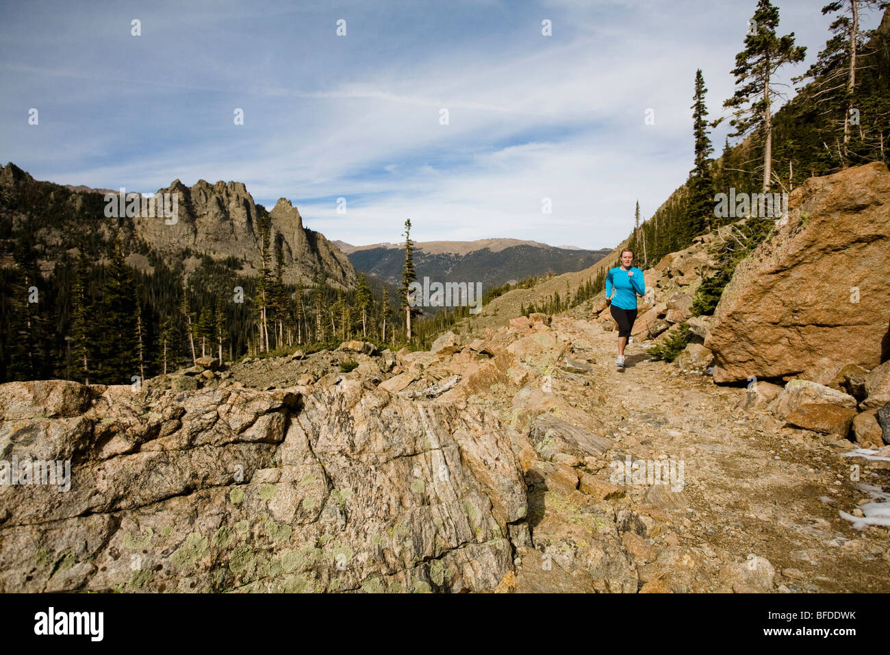 A woman runs along an alpine trail within Rocky Mountain National Park, Colorado. Stock Photo