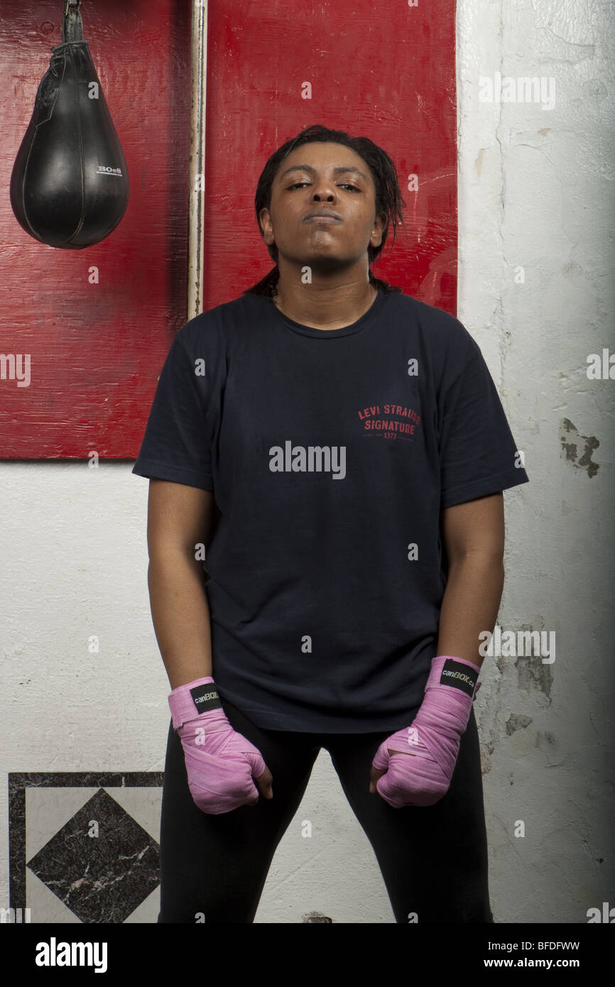 Three quarter length portrait of female boxer in gym with boxing bag