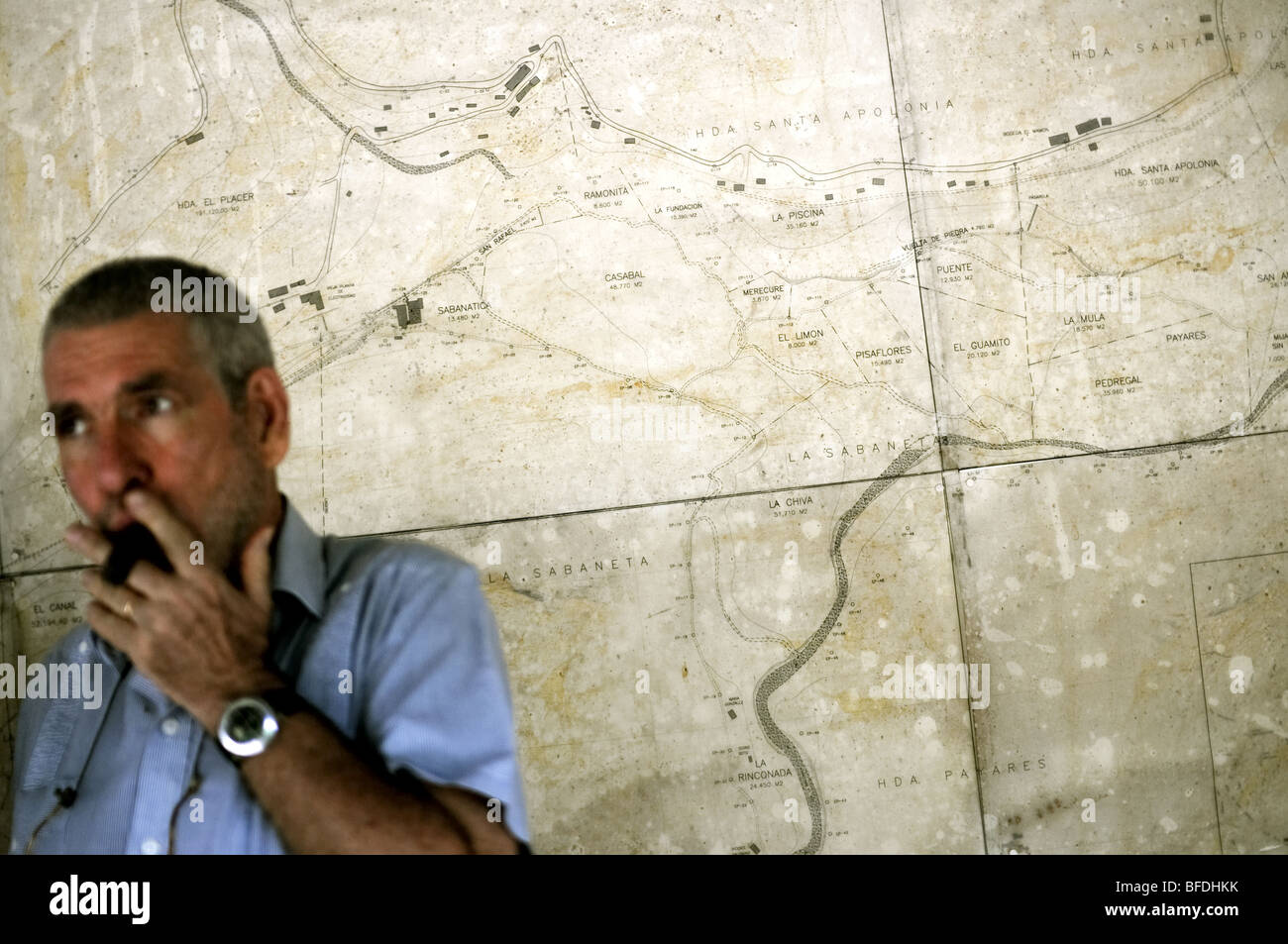 A man smokes a cigar in front of a large map of a cacao plantation in Choroni, Venezuela. Stock Photo