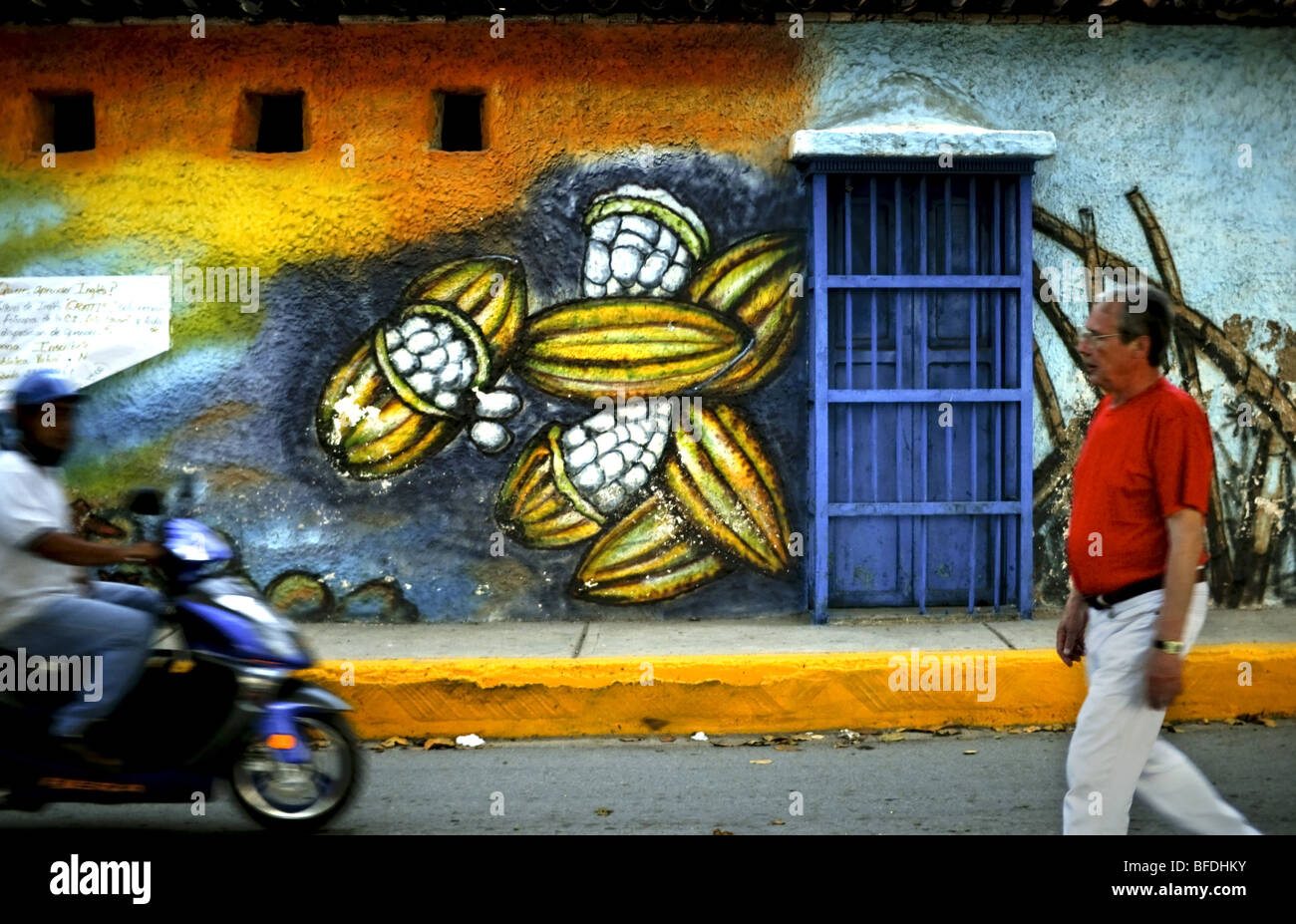 Men pass a street painting of cacao pods in Puerto Colombia, Venezuela. Stock Photo