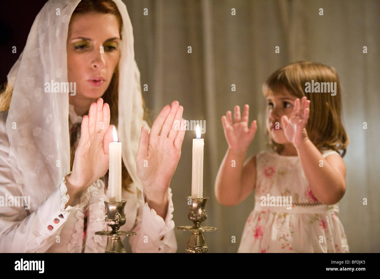 Mother and daughter blessing on Shabbat candles. Stock Photo