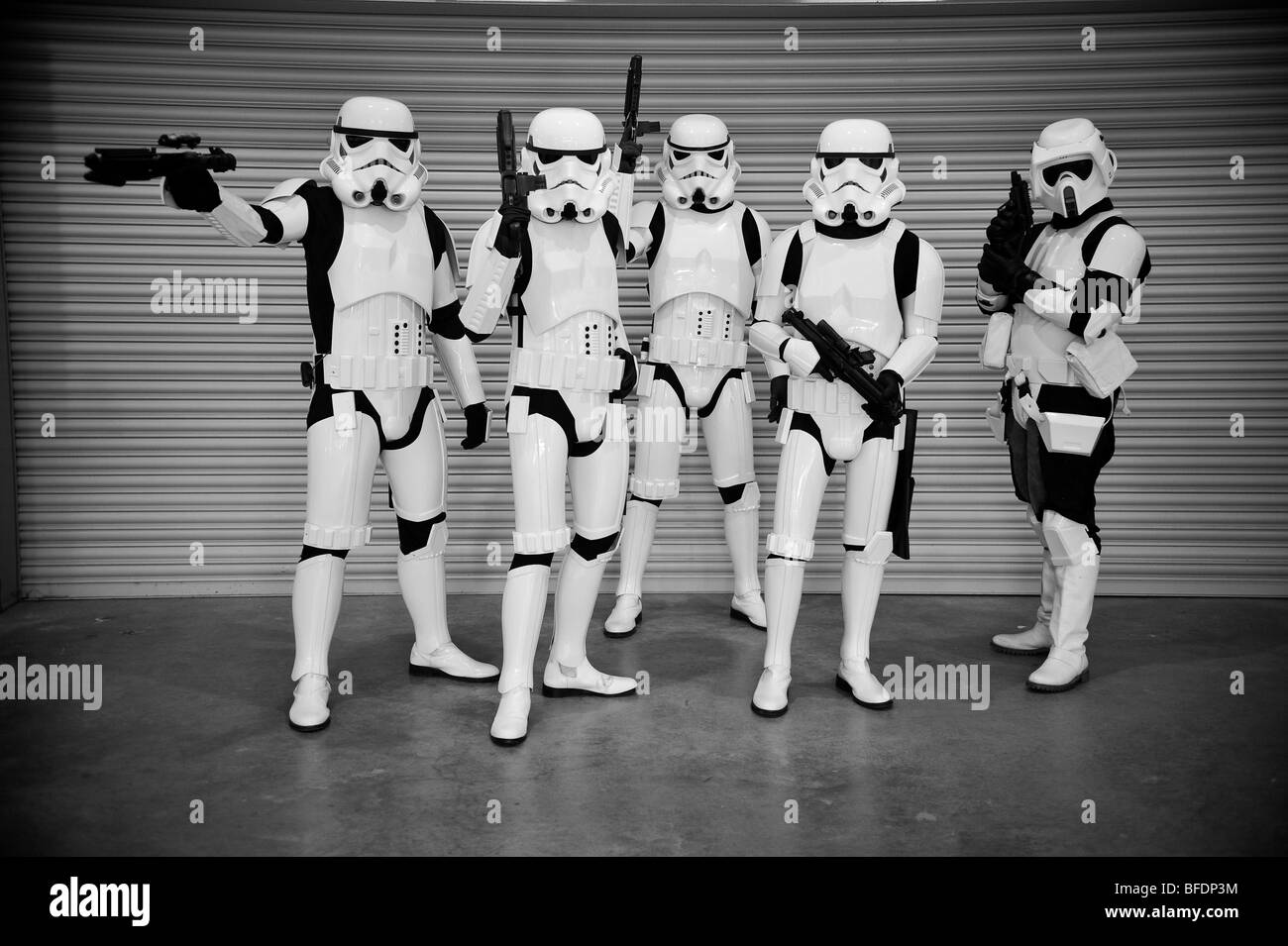 A squadron of Stormtroopers from the Star Wars universe line up ready for battle in front of a corrugated metal wall. Stock Photo