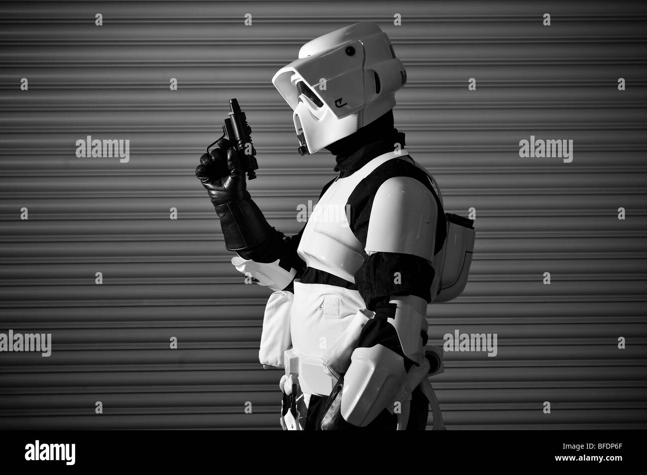 A Stormtrooper from the Star Wars universe ready for battle, standing in front of a corrugated metal wall. Stock Photo