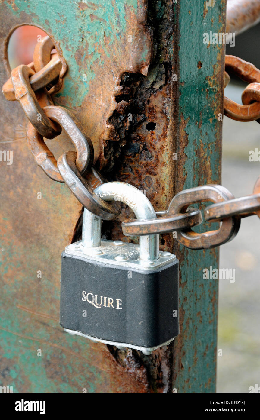 Padlock and rusty chain on old rusted metal gate Stock Photo