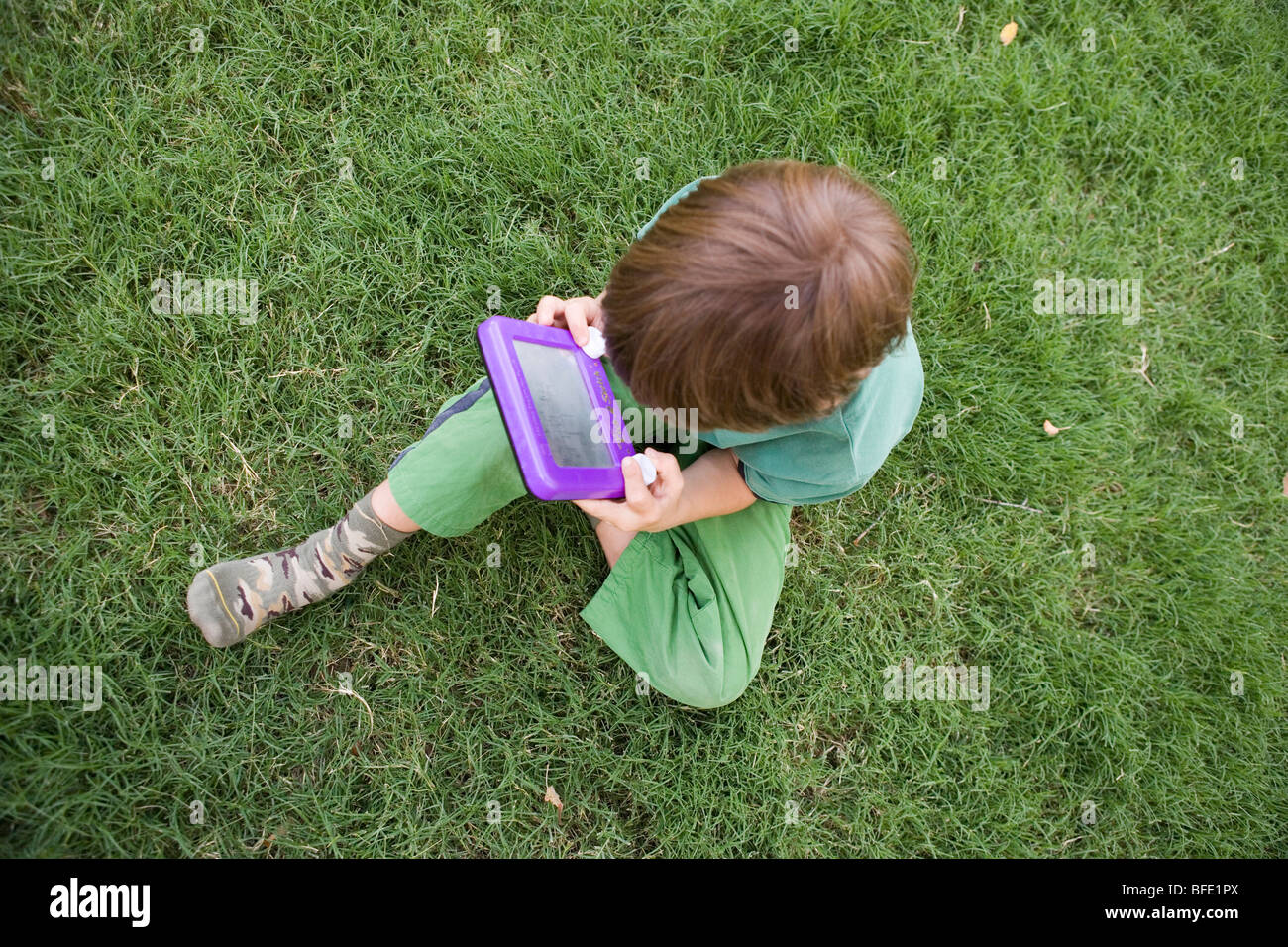 child using an Etch-a-sketch to draw a picture outdoors Stock Photo