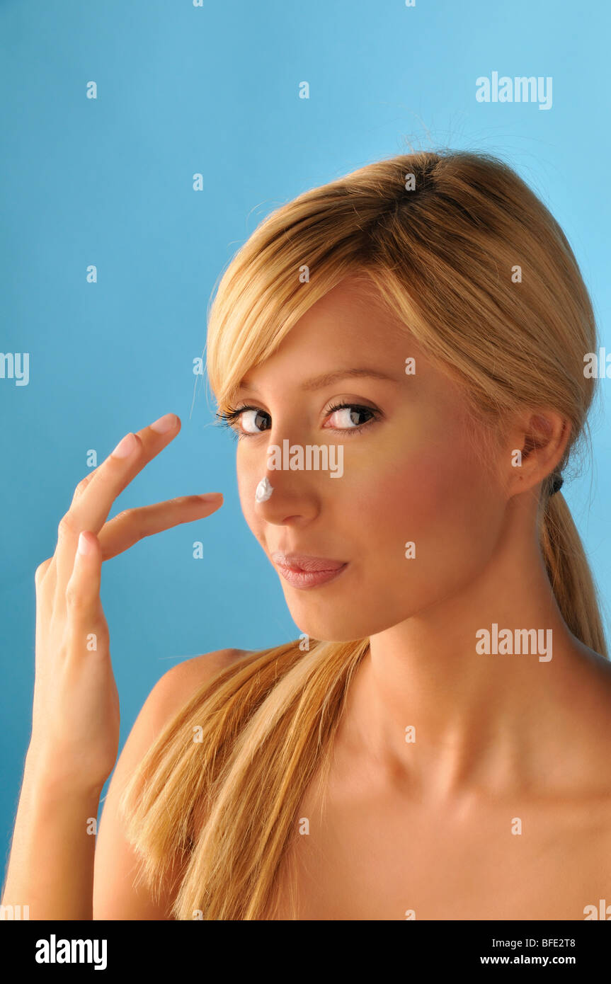 Blond girl creaming her nose Stock Photo