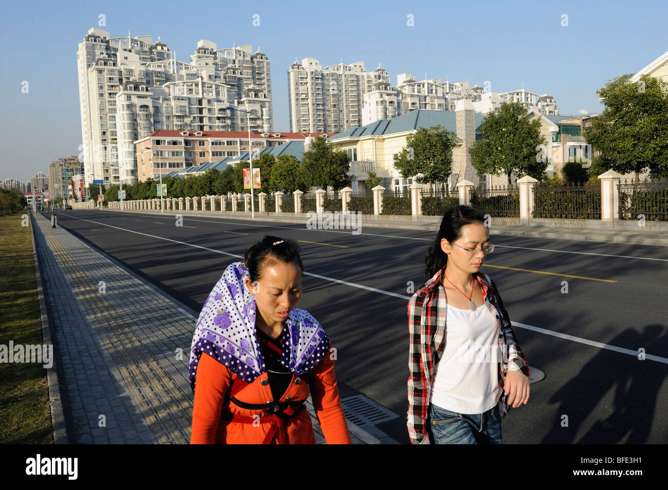 2 ladies walking past a compound of luxurious apartments and villas in Songjiang on the outskirts of Shanghai 2009 Stock Photo