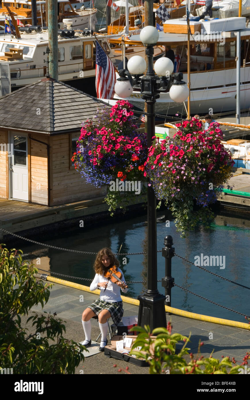 A young fiddler plays beneath flowering hanging baskets at Victoria