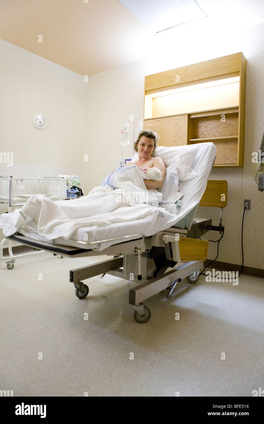 36 year old woman lying in hospital bed with newborn in her arms, Chateauguay, Quebec, Canada Stock Photo