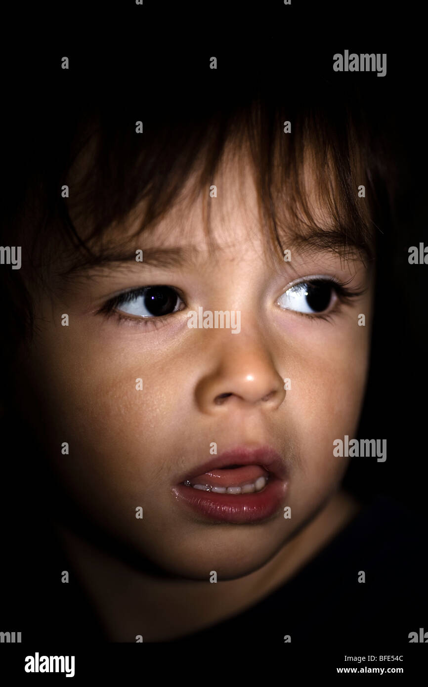 2 1/2 year old boy with dramatic lighting and looking apprehensive, Montreal, Quebec, Canada Stock Photo