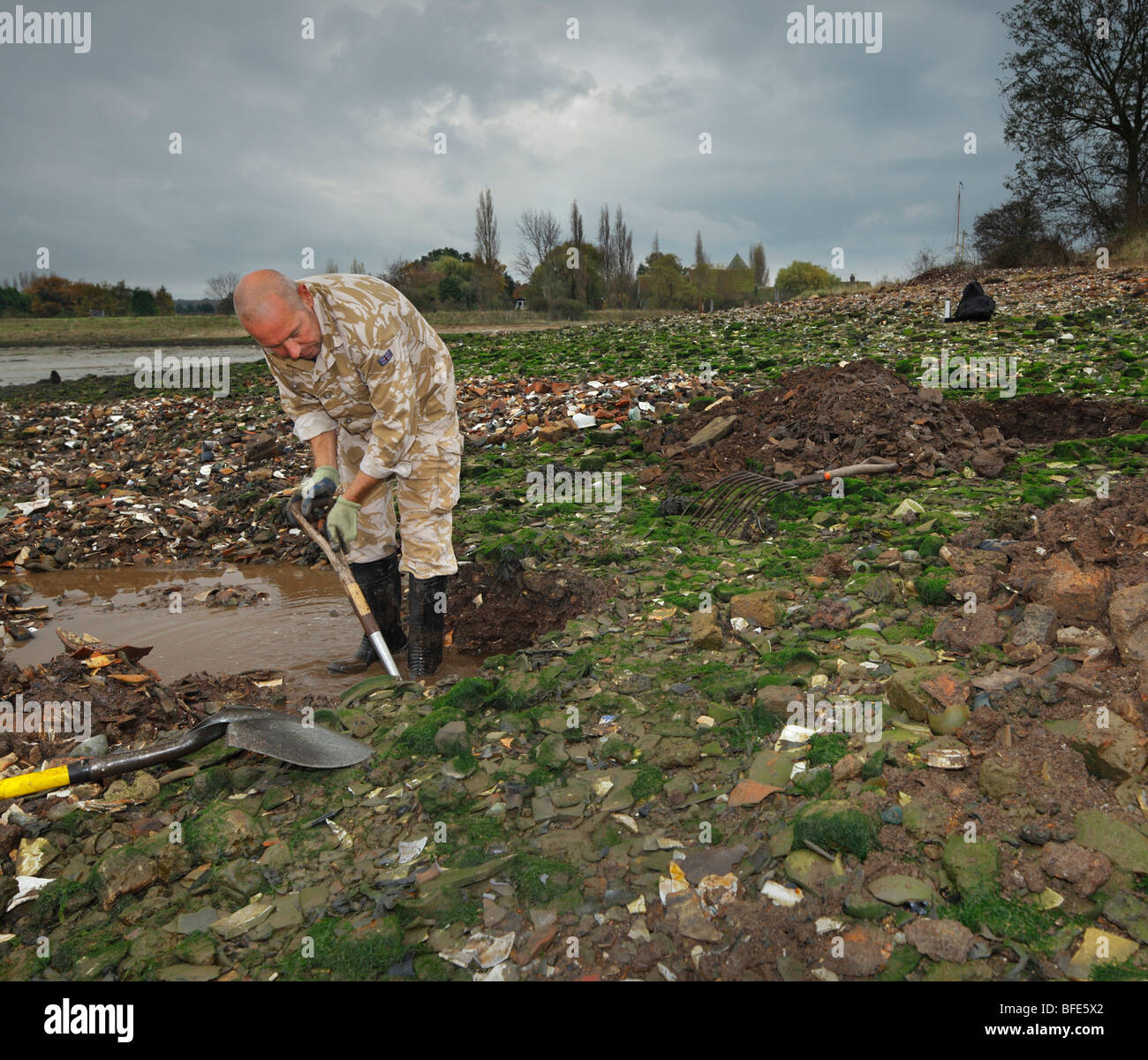 Man digging for antique bottles, in a Victorian dump. Lower Halstow, Kent, England, UK. Stock Photo