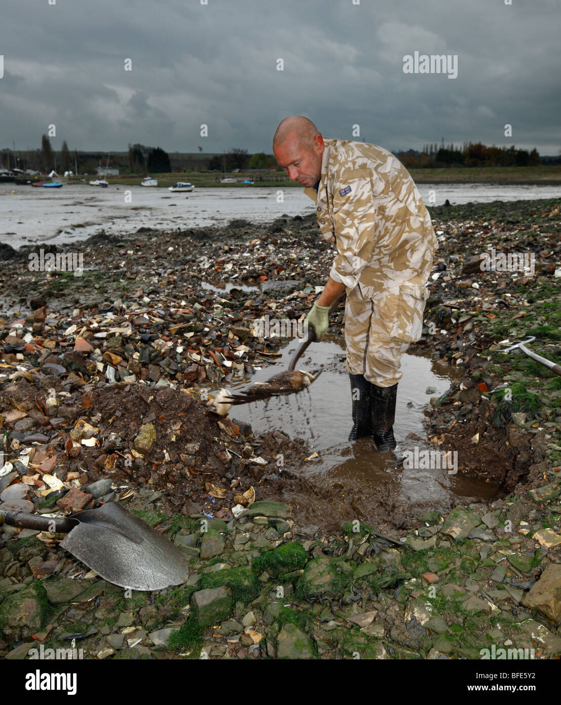 Man digging for antique bottles, in a Victorian dump. Lower Halstow, Kent, England, UK. Stock Photo