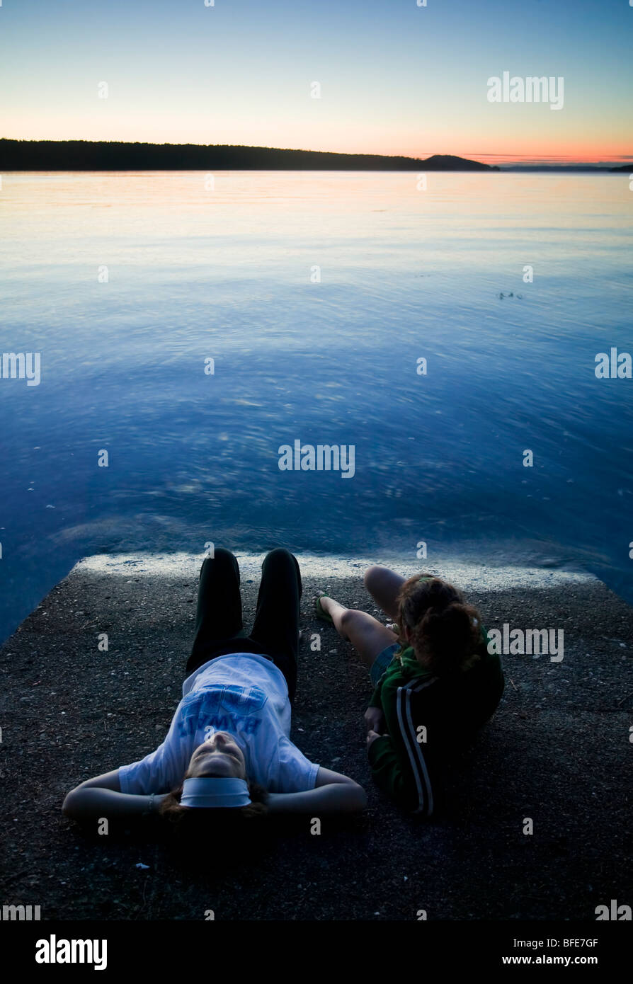 Two women relaxing enjoying the setting sun, Salt Spring Island, Gulf Islands, British Columbia, Canada Stock Photo
