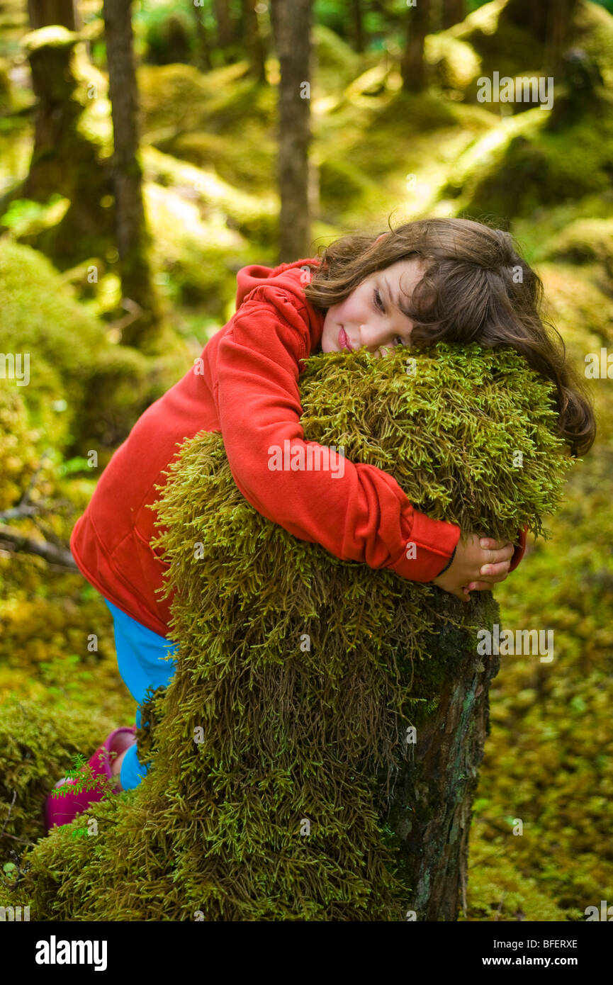 Girl hugging moss covered stump, Naikoon Provincial Park, Queen Charlotte Islands, British Columbia, Canada Stock Photo