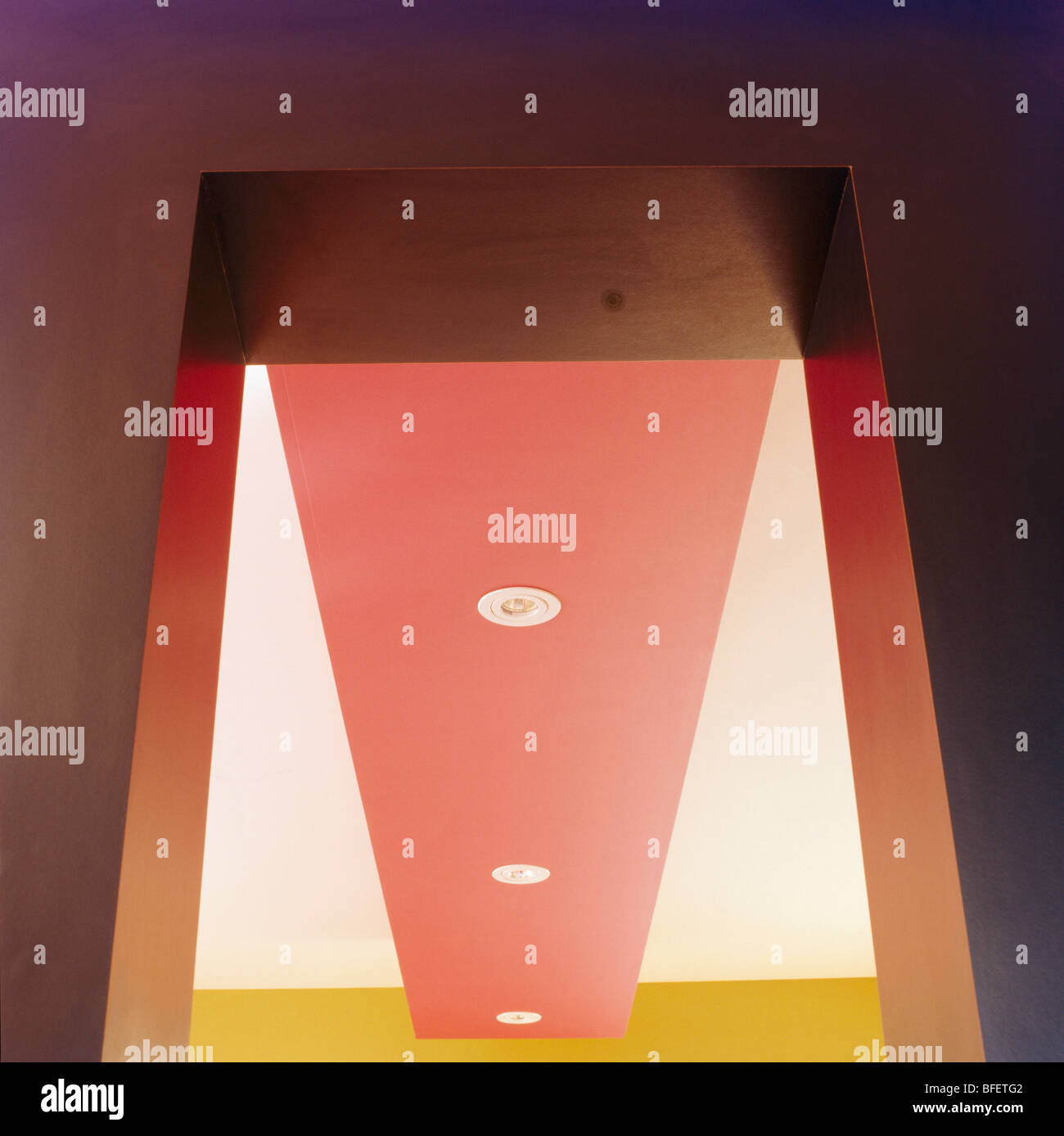 Upward closeup view of modern red and white ceiling with recessed