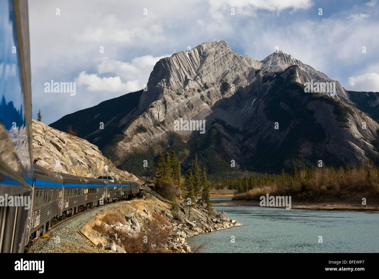 Passenger train riding along the Athabasca River in Jasper National Park, Alberta, Canada Stock Photo