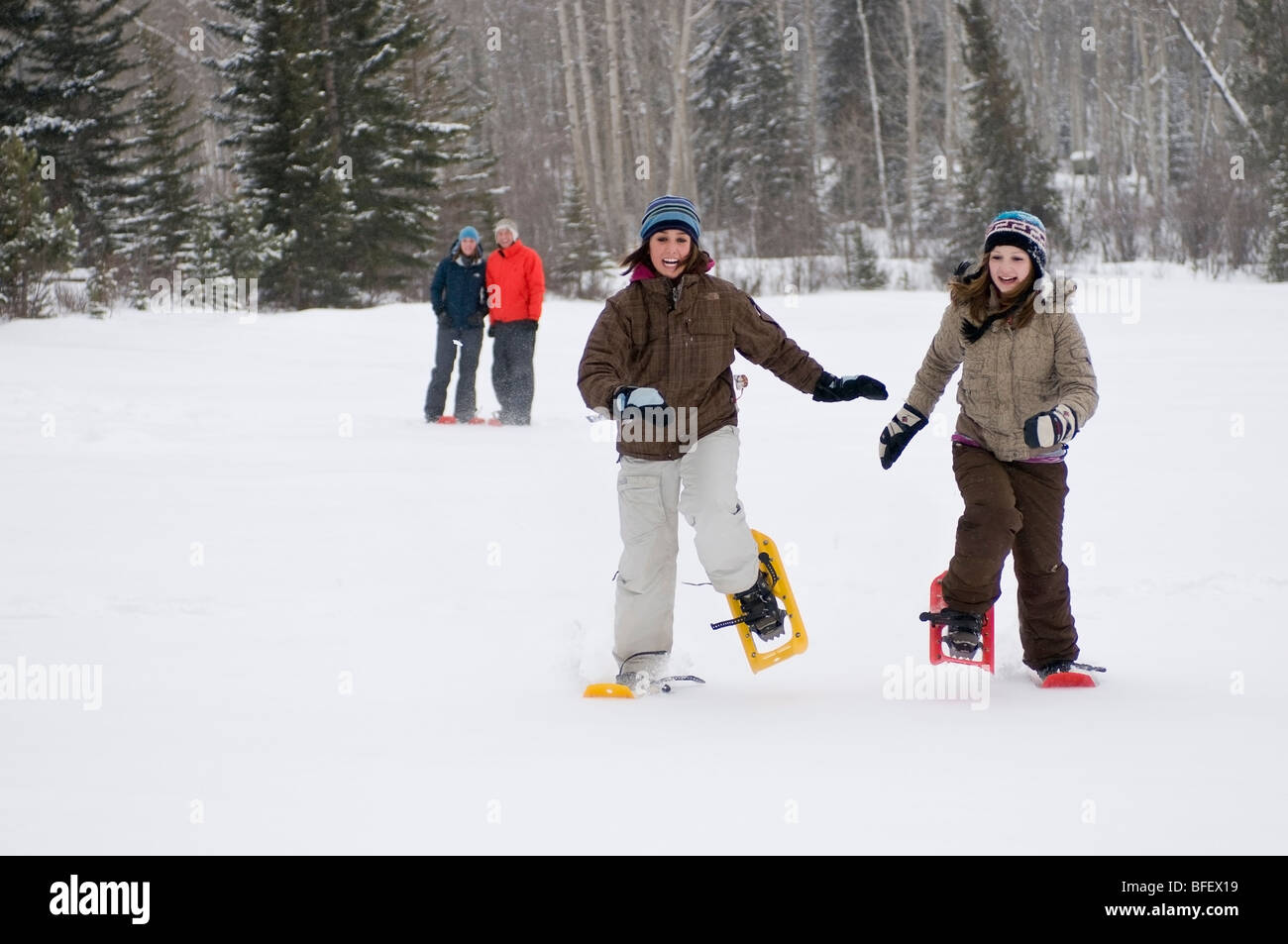Two young girls race across Pyramid lake in snowshoes as parents look