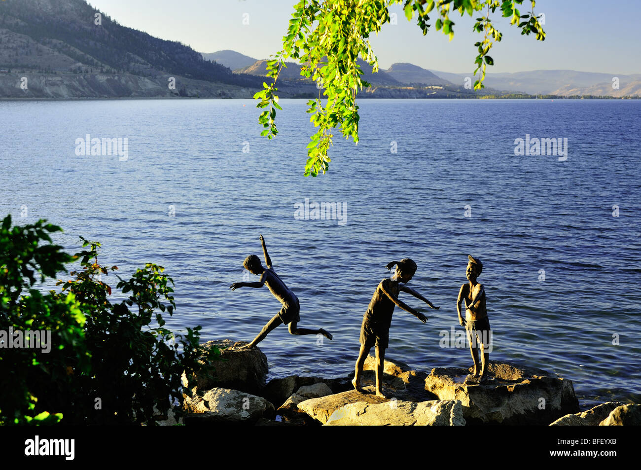 Statues of children playing on rocks near waters edge in Penticton, BC. Stock Photo