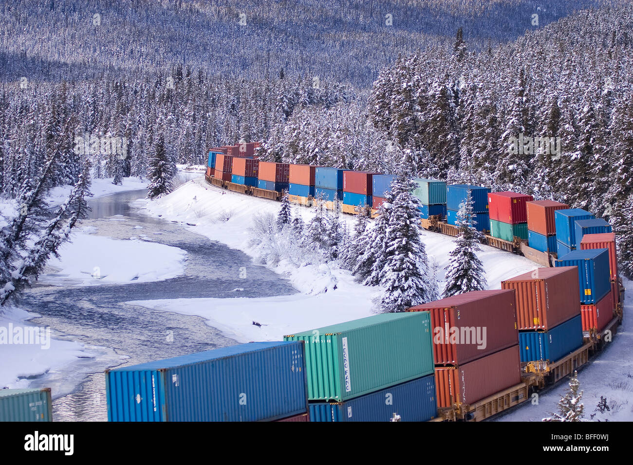 Container Train, Bow River and snow covered trees in winter. Banff National Park, Alberta. Stock Photo