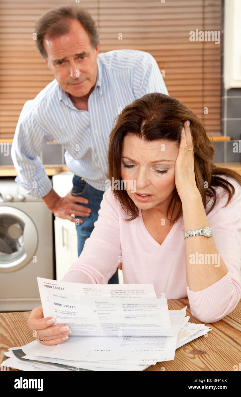 Woman looks worried reading a bill, man looks on concerned. Stock Photo