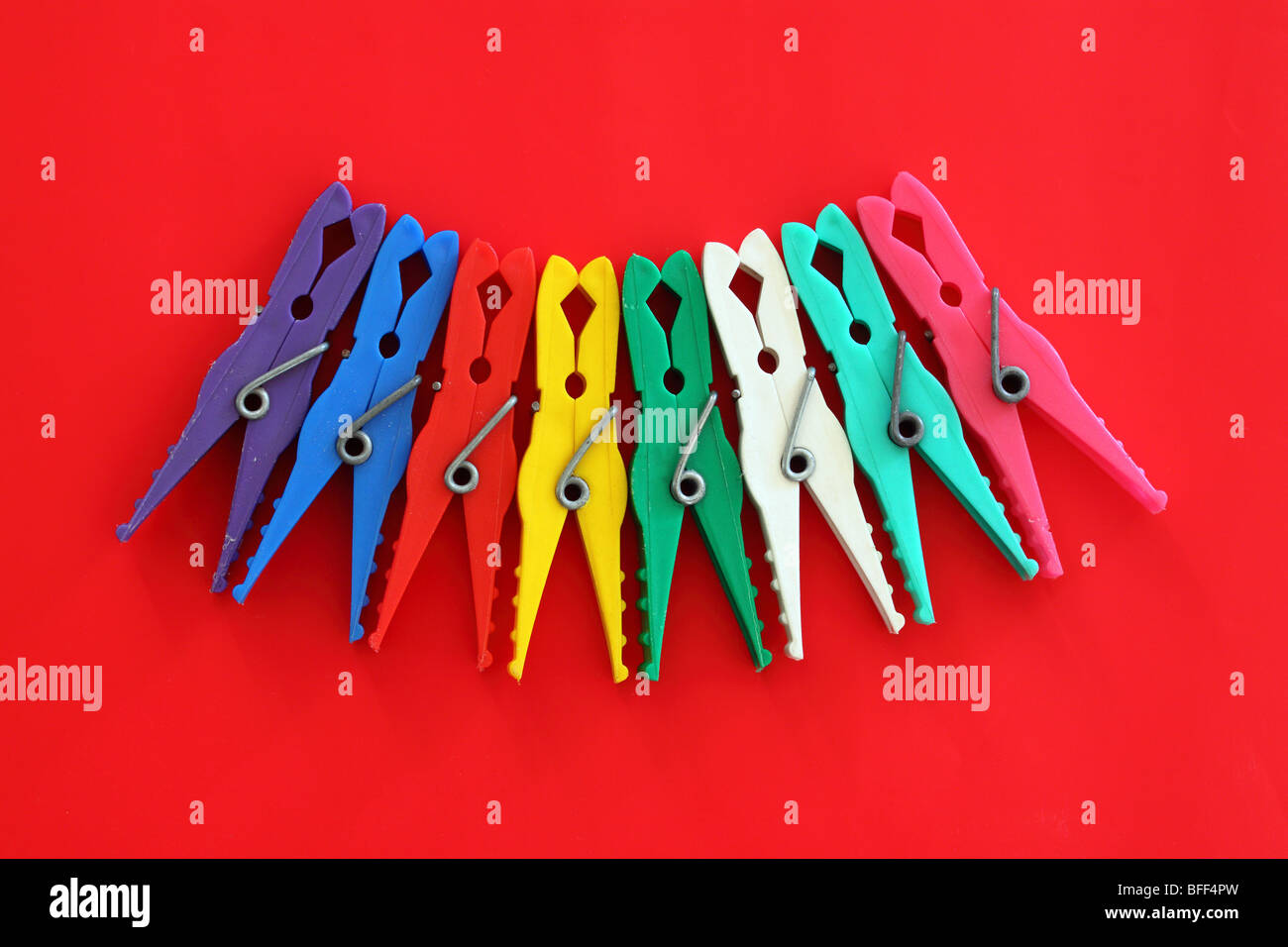 Multicolor laundry clips on red background Stock Photo