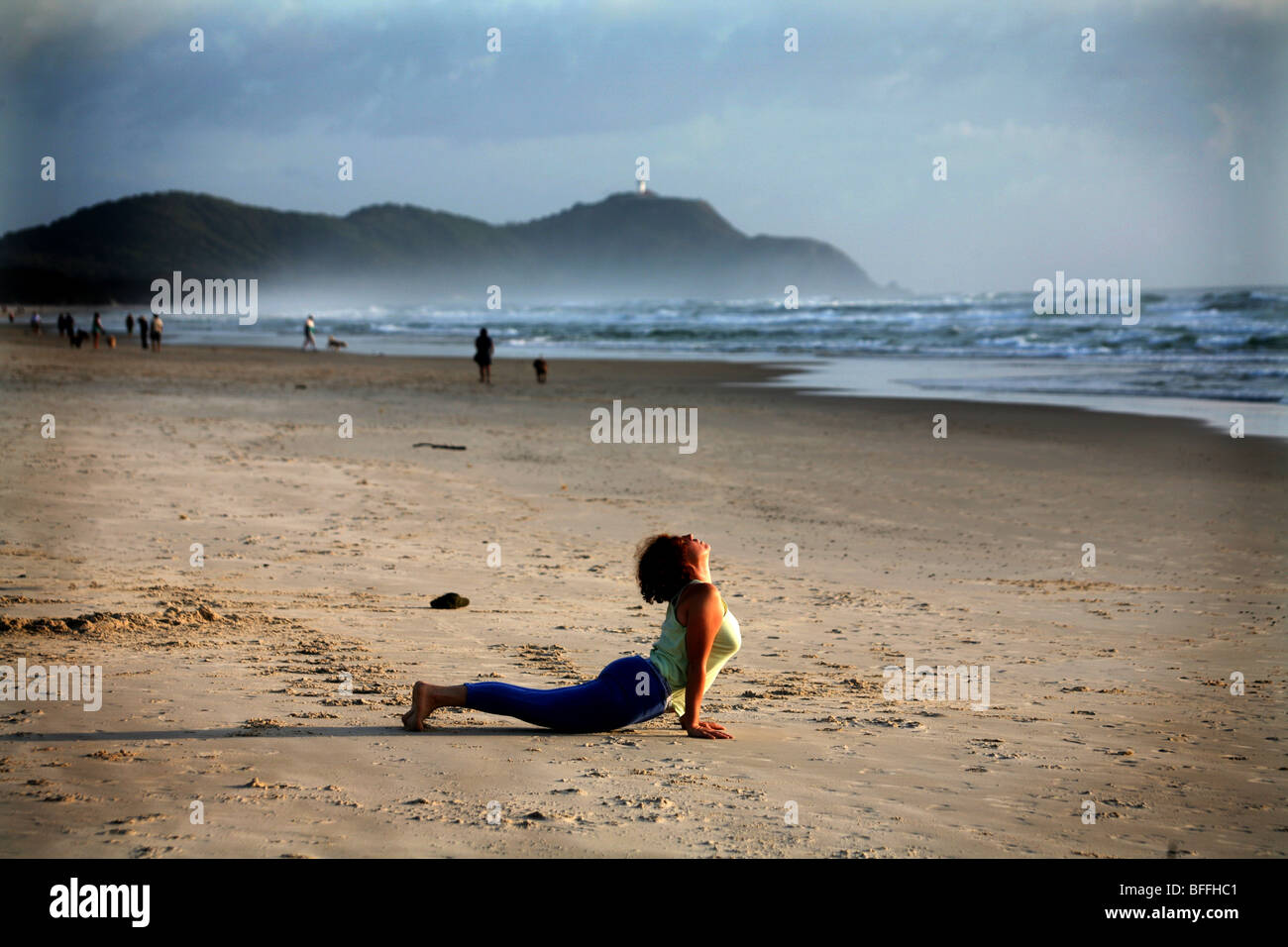 A woman arches her back in the Cobra pose during a morning yoga program at Tallow beach Stock Photo