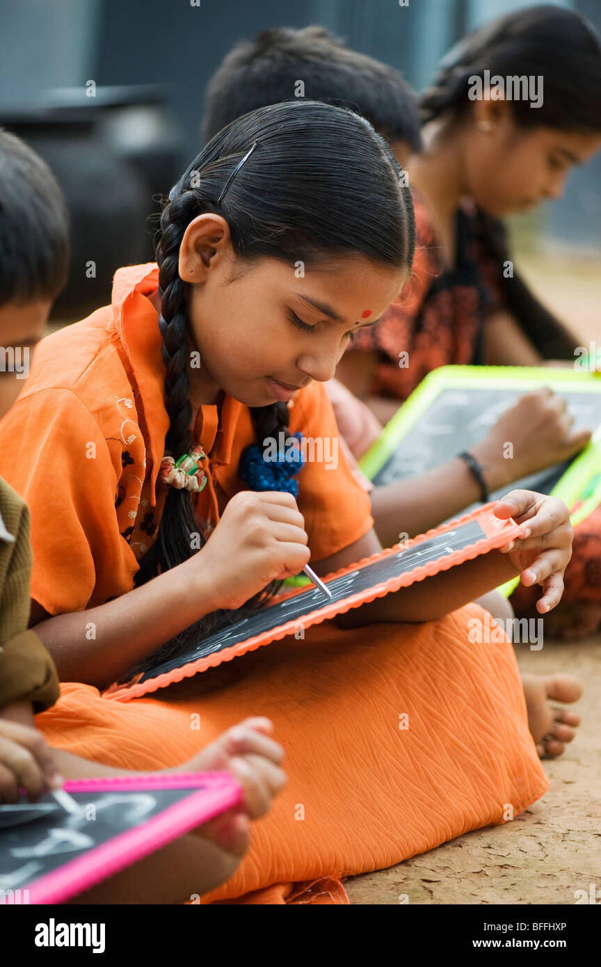 Indian school children sitting outside their school writing on chalkboards. Andhra Pradesh, India Stock Photo