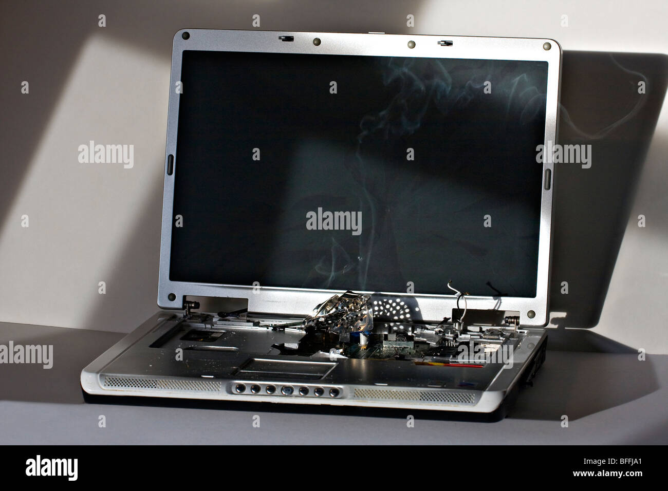 Broken Laptop Computer. Screen cracked with smoking computer components. Stock Photo