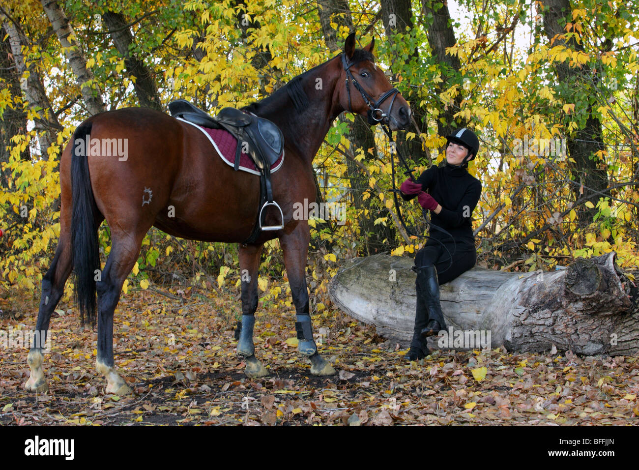 A young girl leads her horse back to stables along a woodland path
