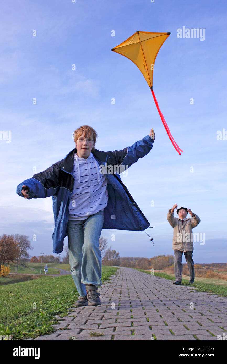 teenage boy and his grandfather flying a kite Stock Photo