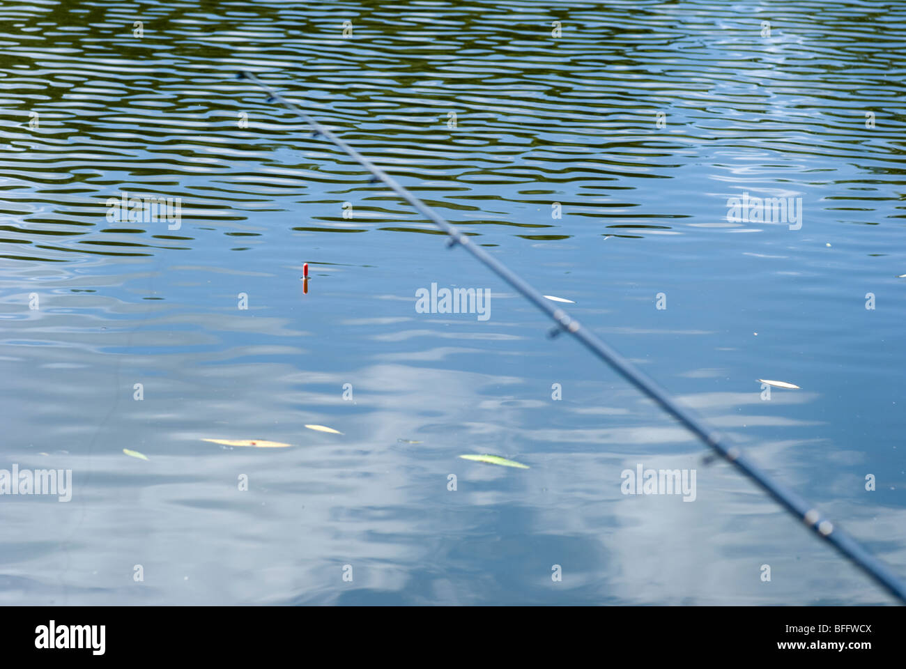 Fishing rod and float against blue rippled water Stock Photo