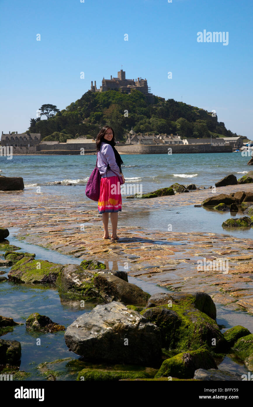 Portrait of a Chinese female Tourist crossing the tidal Causeway at St Michaels Mount, Marazion, near Penzance in Cornwall, UK Stock Photo