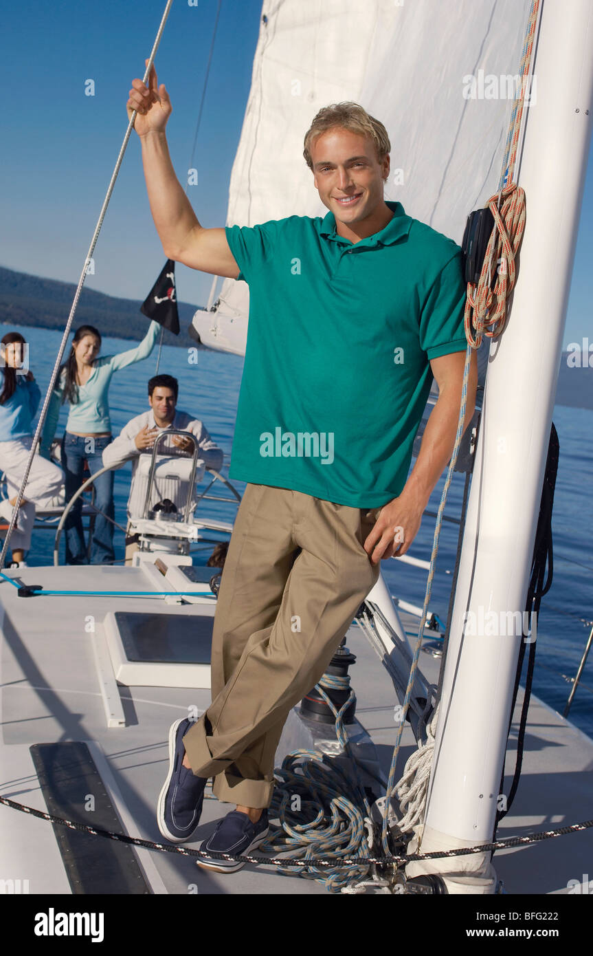 Young man on sailboat, friends in background, (portrait) Stock Photo