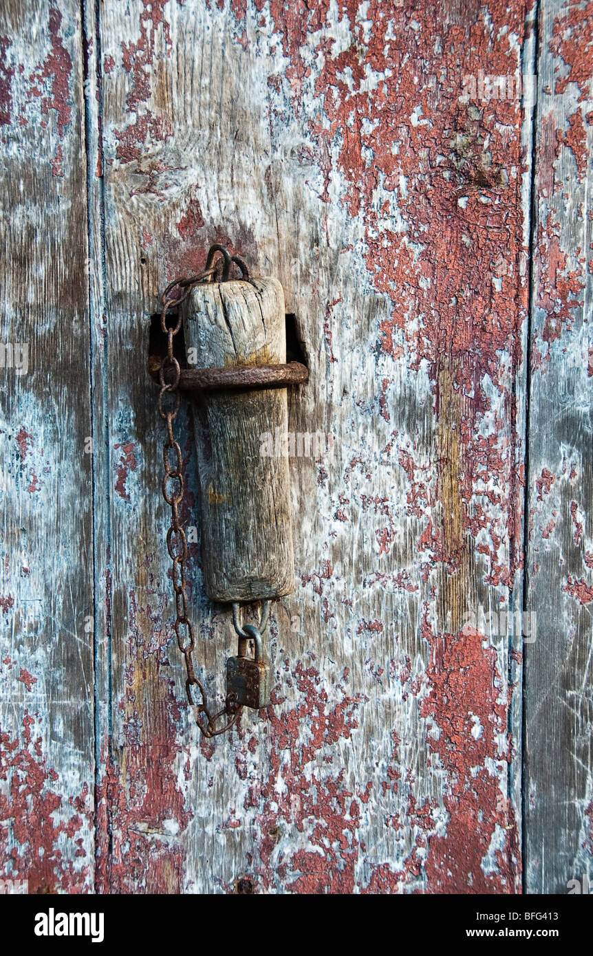 Tradition wooden door stop on a barn door with fading red paint in the