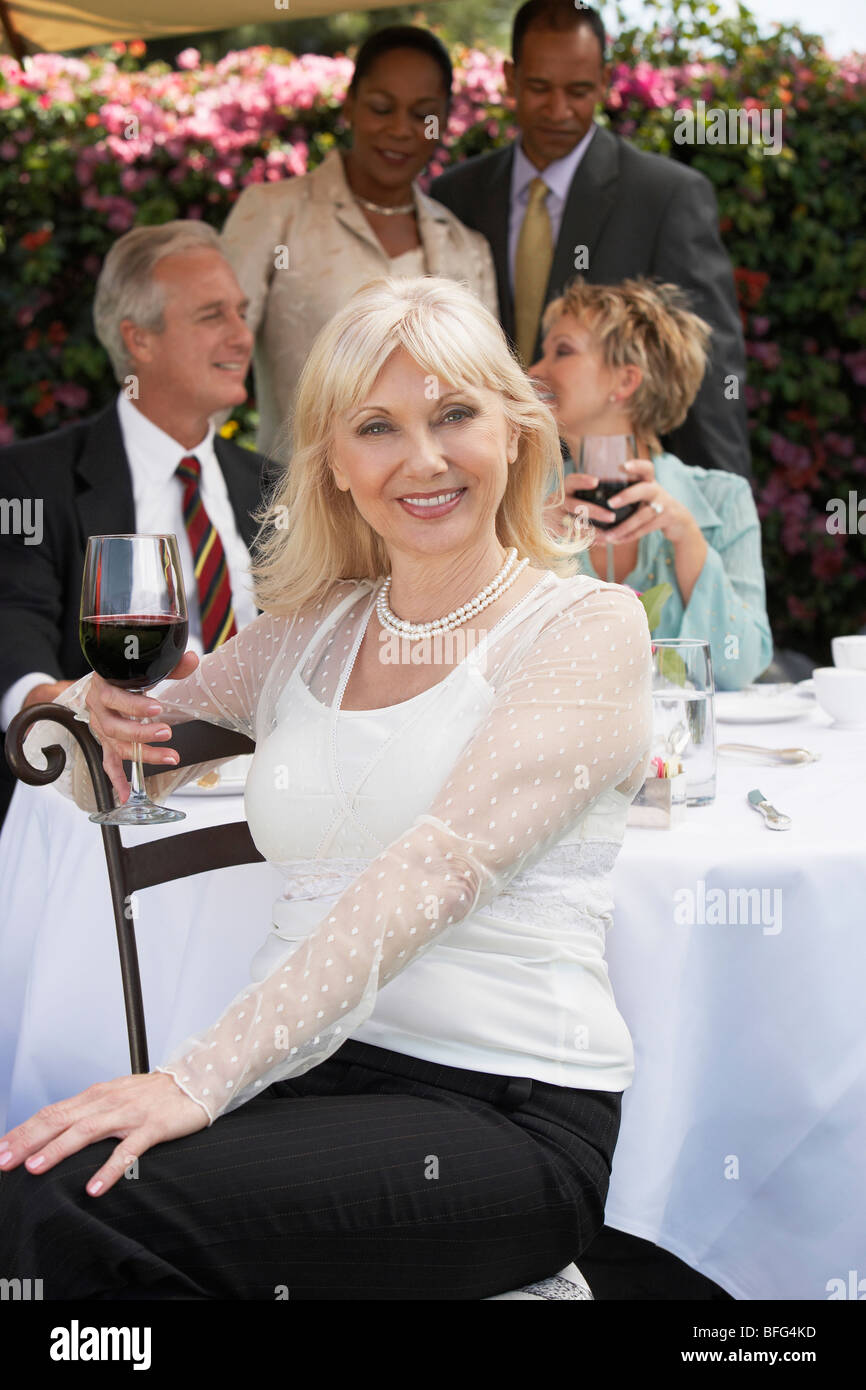 Elegant woman sitting holding wine glass at garden party Stock Photo ...