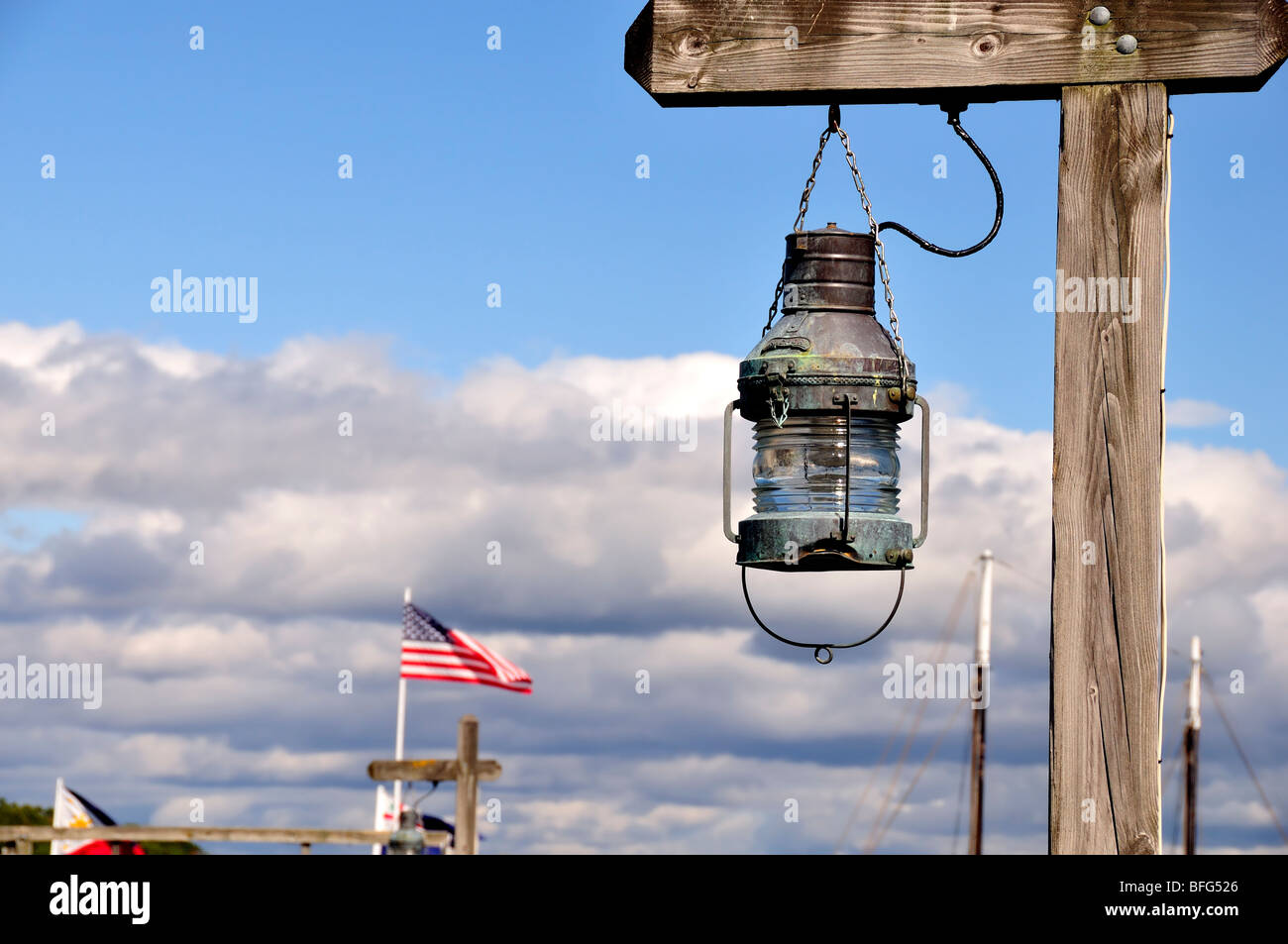An old lantern hangs from a weathered, wooden post above a dock in Bar