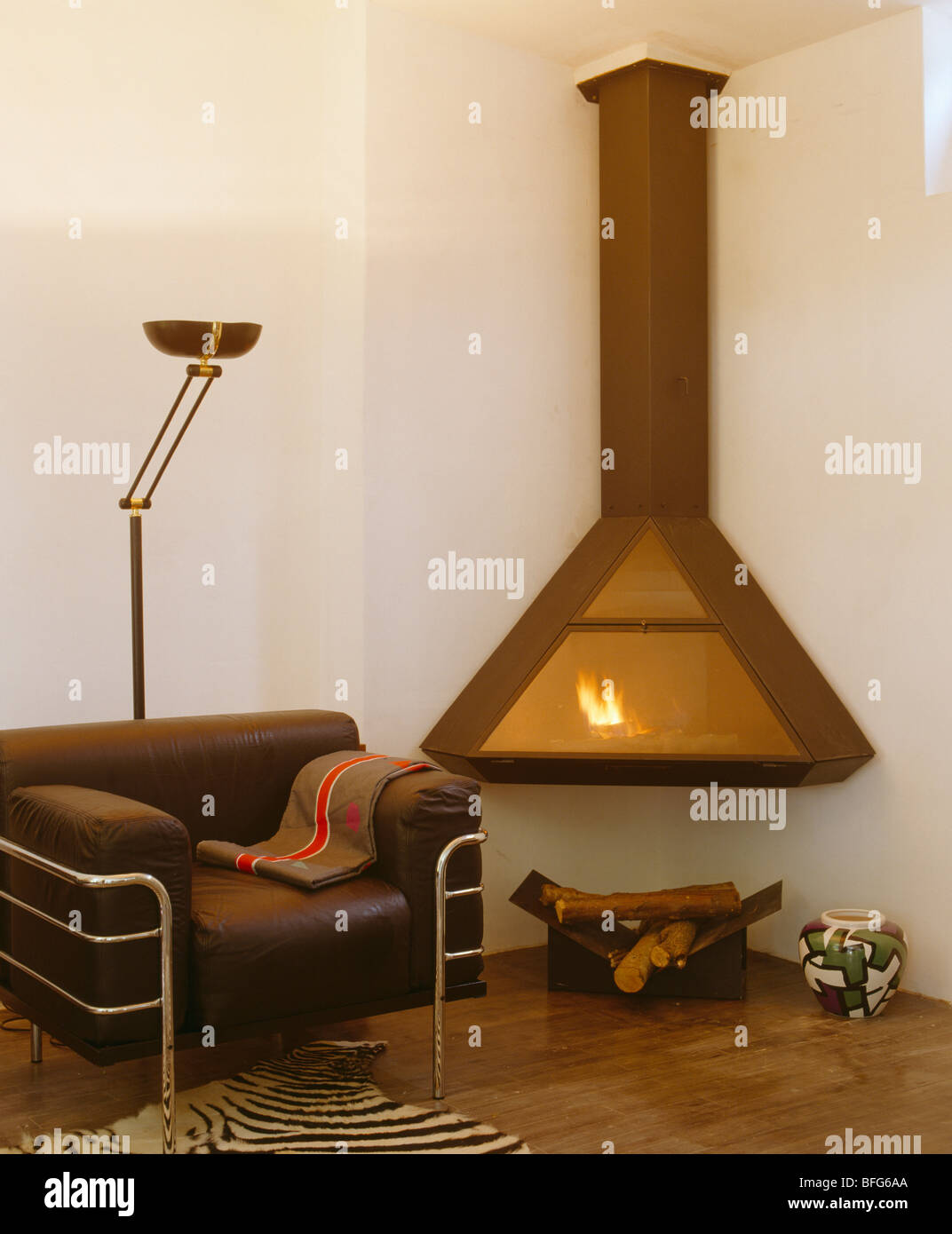 Brown leather+chrome armchair beside wallmounted modern fireplace in