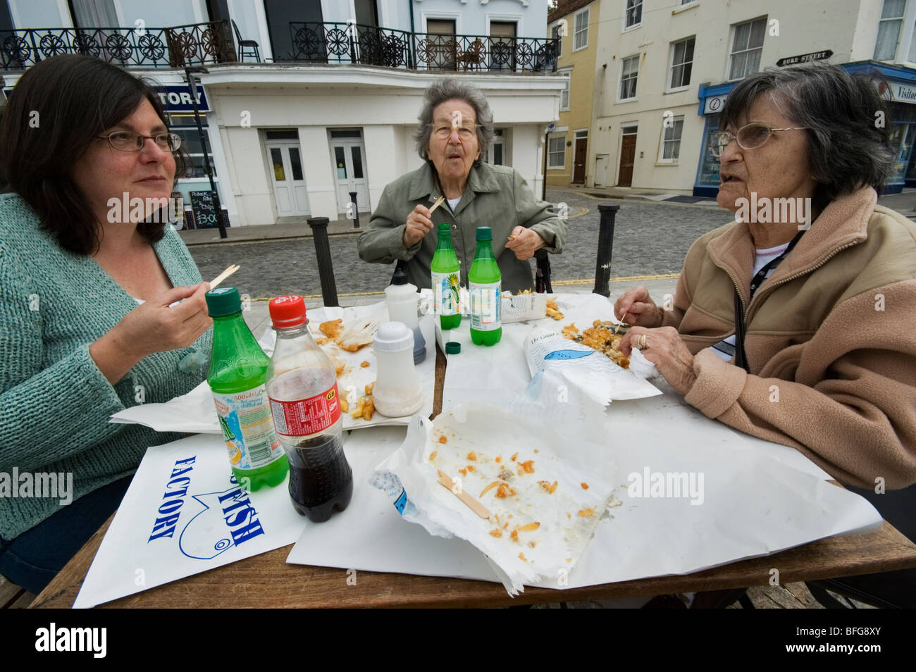 Three women eating fish and chips out of the paper on Margate seafront MODEL RELEASED. Stock Photo