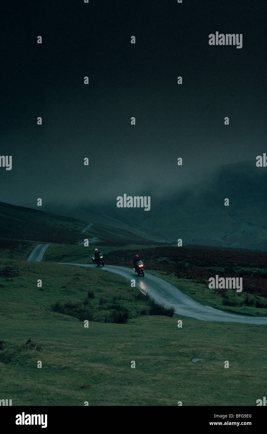 Two motorbikes and riders on a wet Welsh road Stock Photo