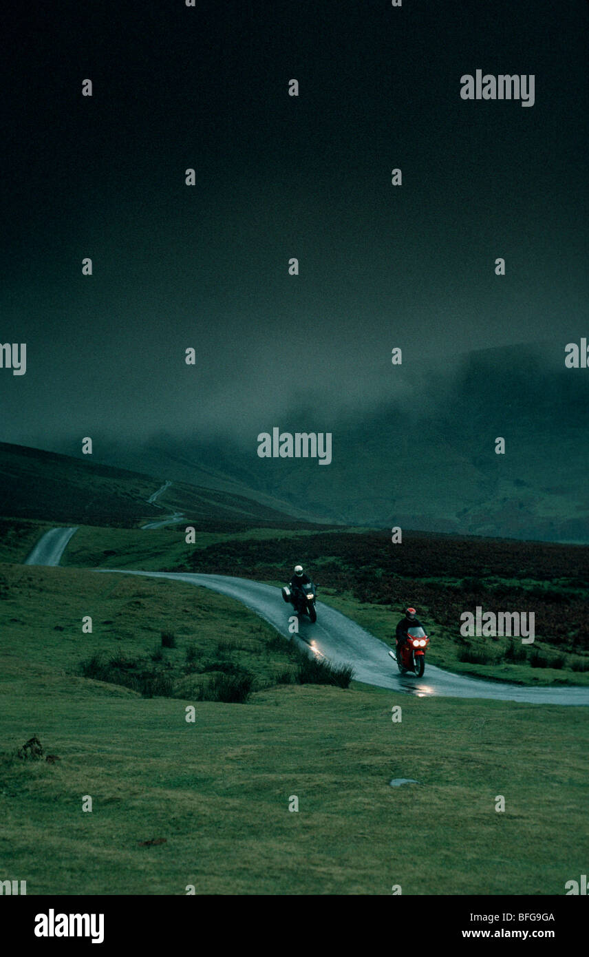 Two motorbikes and riders on a wet Welsh road Stock Photo