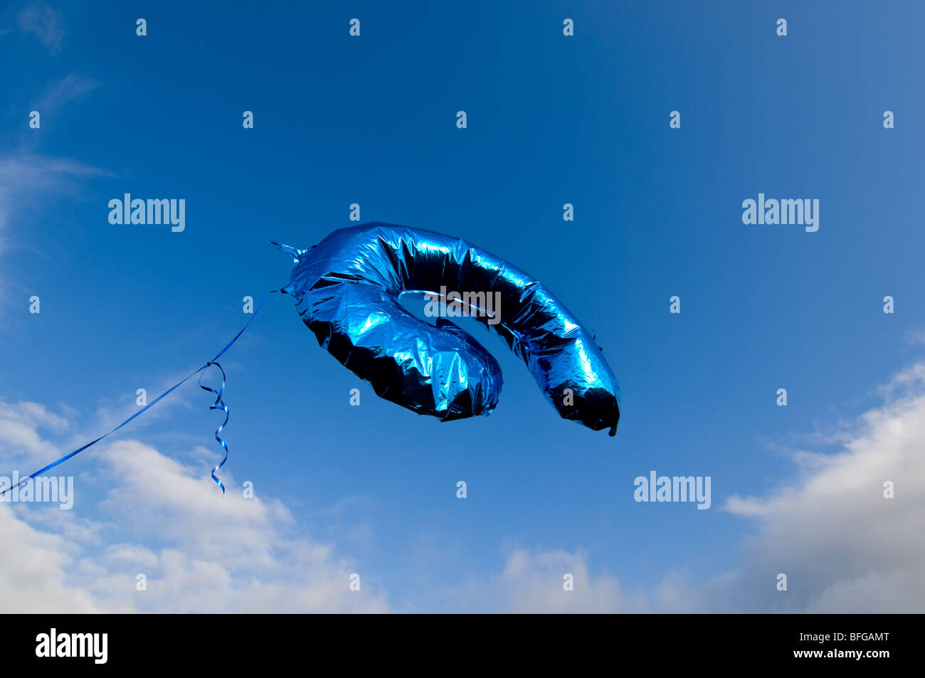A floating blue balloon in the shape of a number six or number nine. Stock Photo