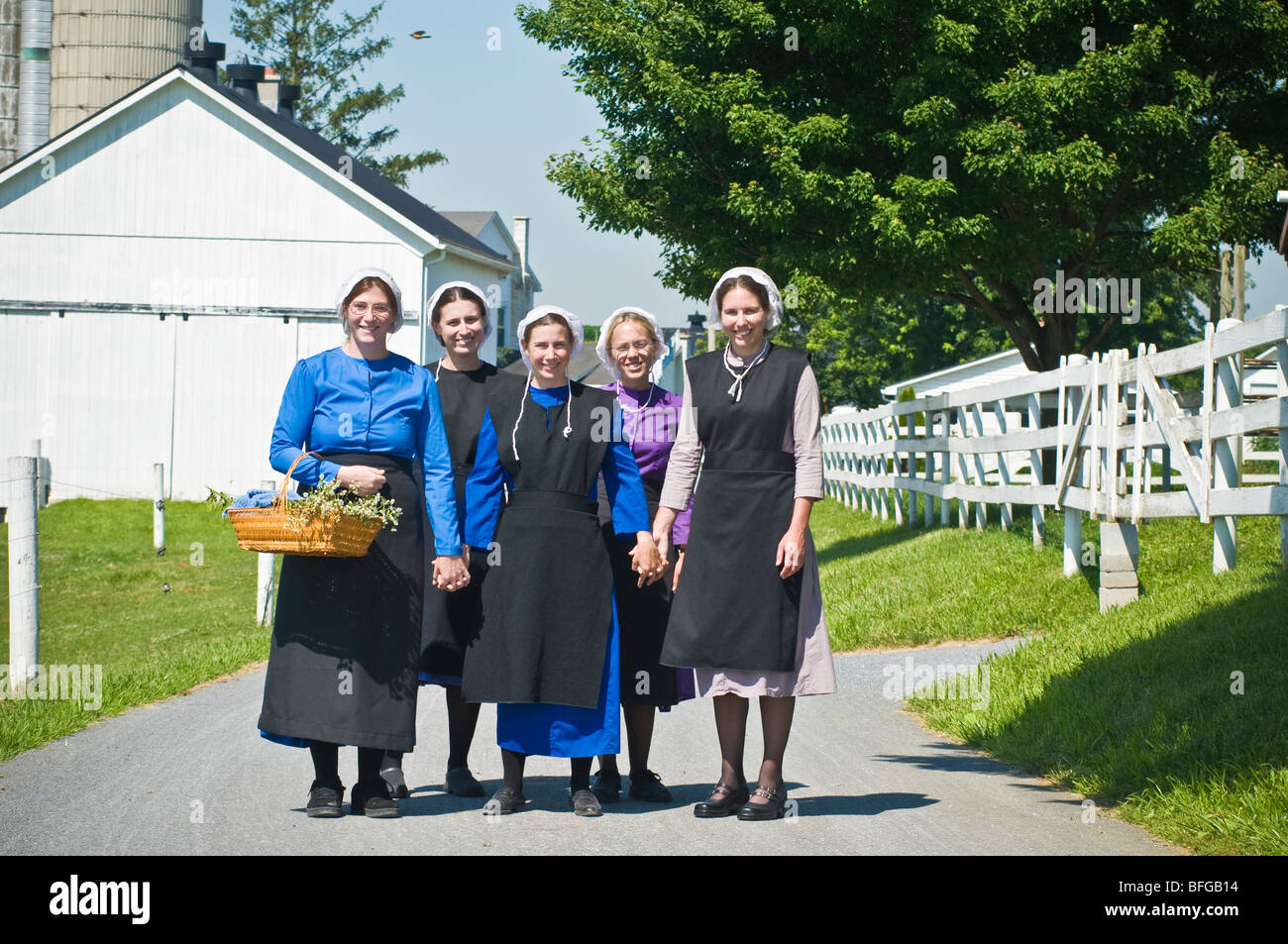 Young amish women friends walking down country lane road in Lancaster