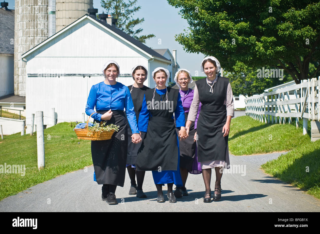 Young amish women friends walking down country lane road in Lancaster ...