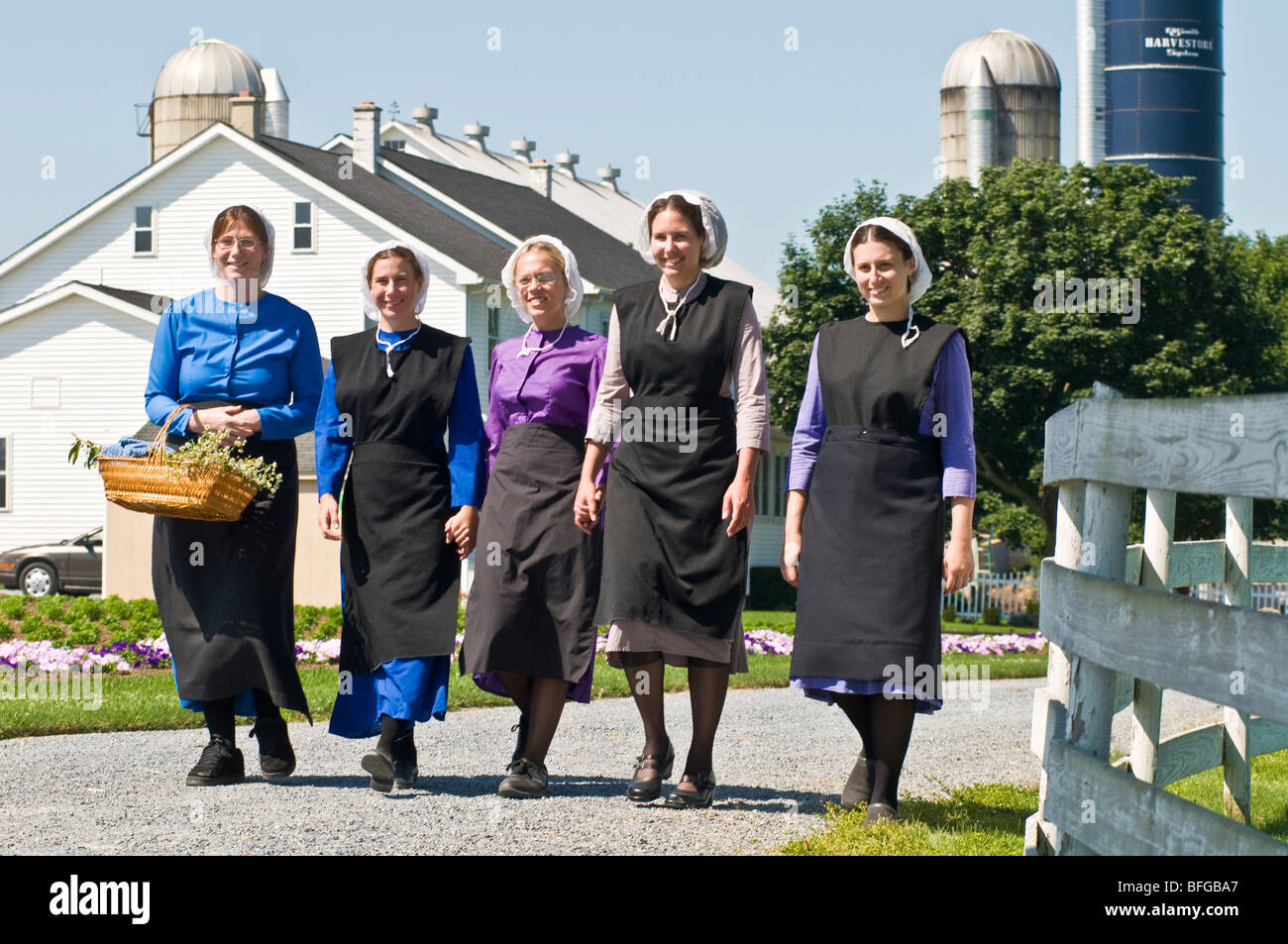 Young amish women friends walking down country lane road in Lancaster ...